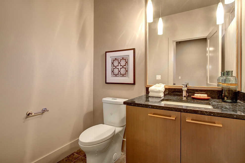 Esempio di un piccolo bagno di servizio minimalista con ante lisce, ante in legno scuro, WC a due pezzi, pareti beige, pavimento in marmo, lavabo sottopiano, top in marmo, pavimento marrone e top nero