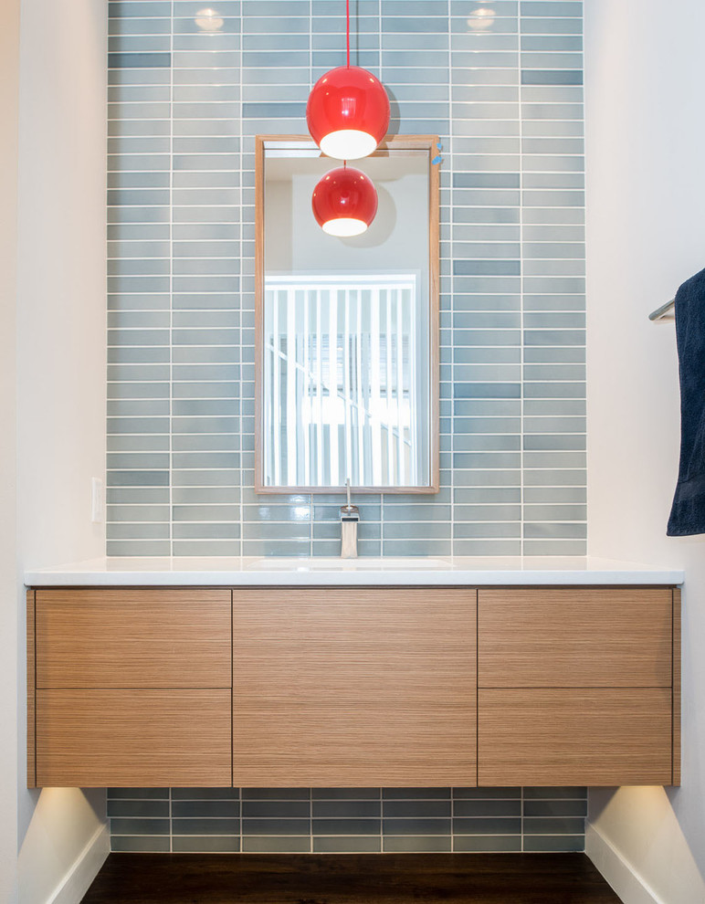 Cette image montre un WC et toilettes minimaliste en bois clair avec un lavabo encastré, un placard à porte plane, un plan de toilette en quartz modifié, un carrelage bleu, des carreaux de céramique et parquet foncé.