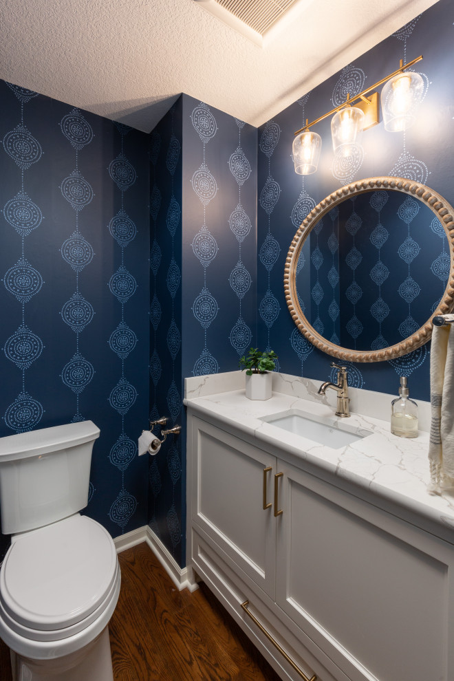 Klassisk inredning av ett litet vit vitt toalett, med skåp i shakerstil, vita skåp, blå väggar, mellanmörkt trägolv, ett undermonterad handfat och bänkskiva i kvarts