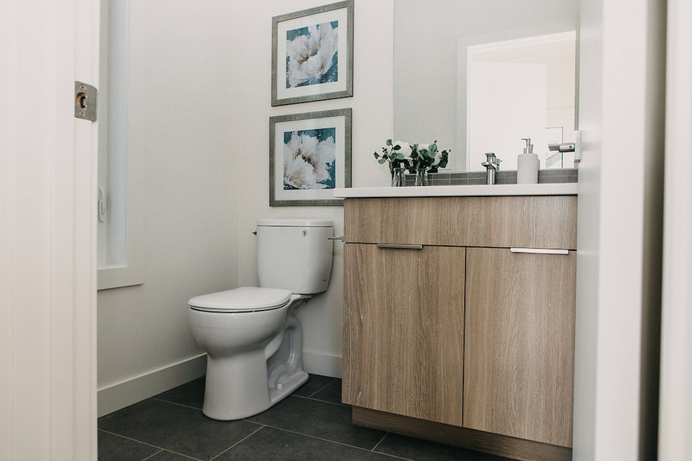 Modern inredning av ett mellanstort vit vitt toalett, med skåp i shakerstil, skåp i ljust trä, en toalettstol med hel cisternkåpa, vita väggar, ett undermonterad handfat och svart golv