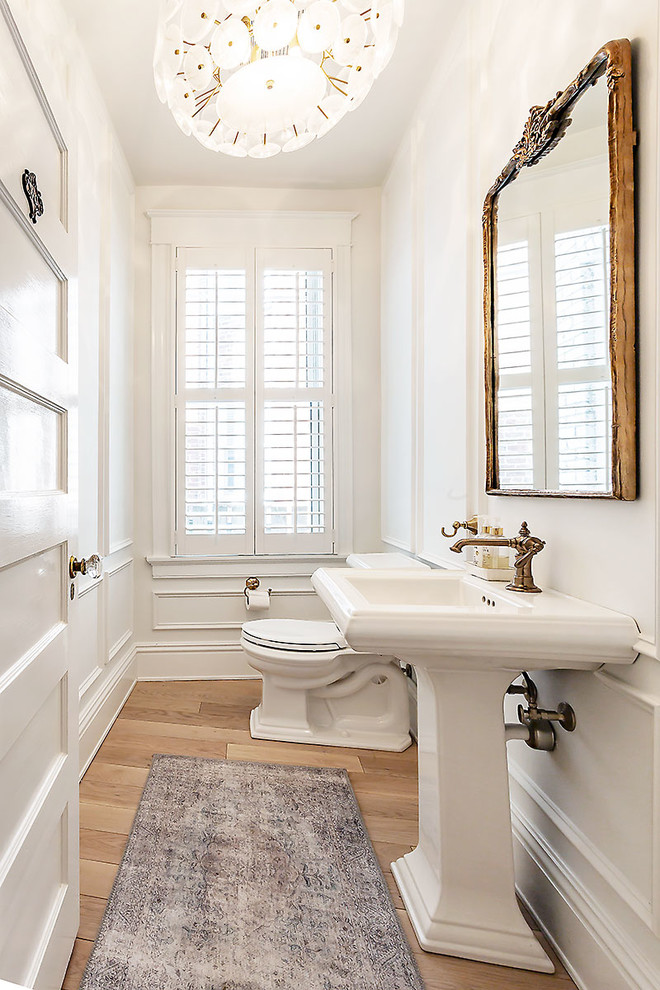 Esempio di un piccolo bagno di servizio tradizionale con WC a due pezzi, pareti bianche, parquet chiaro e lavabo a colonna