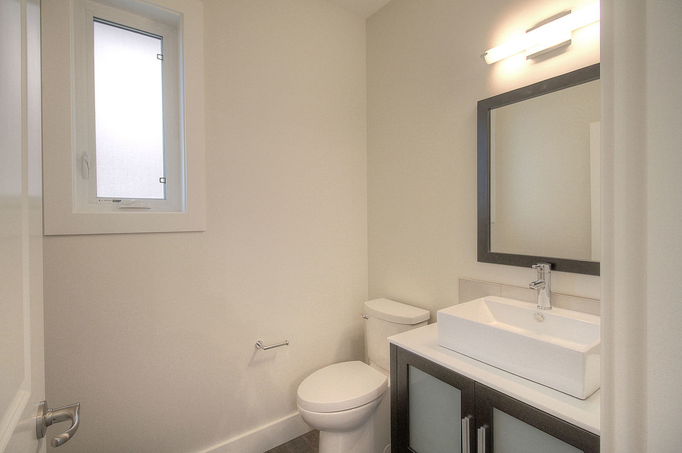 バンクーバーにある高級な小さなモダンスタイルのおしゃれなトイレ・洗面所 (シェーカースタイル扉のキャビネット、茶色いキャビネット、横長型シンク、分離型トイレ、白い壁、クッションフロア) の写真