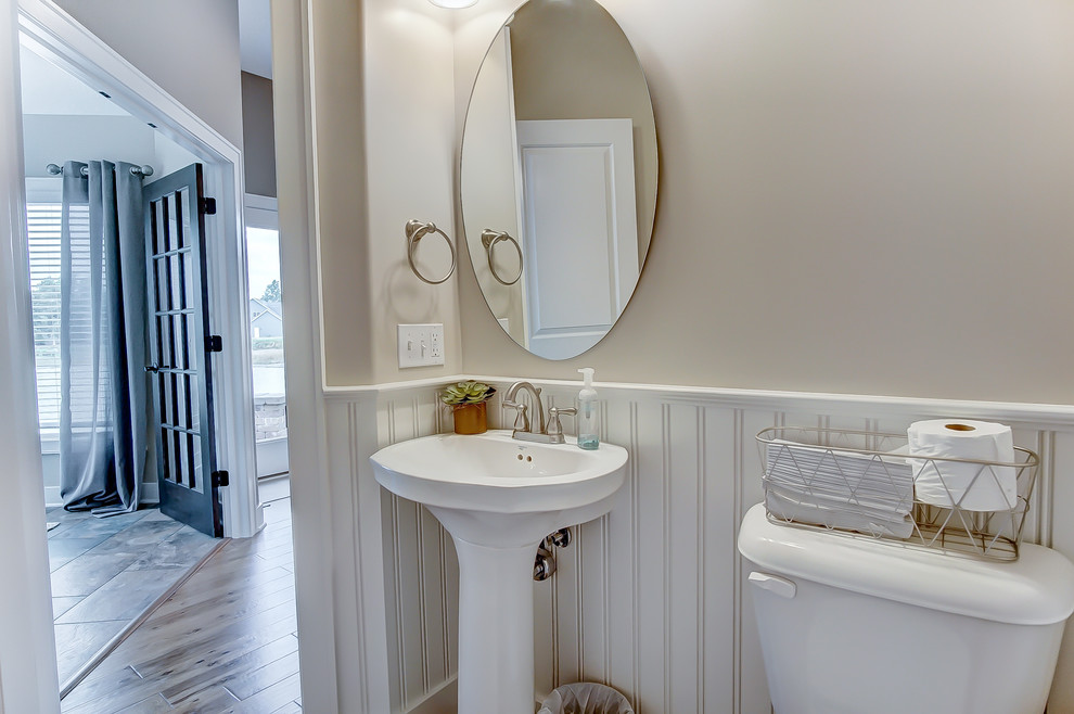 Foto på ett mellanstort amerikanskt vit toalett, med en toalettstol med hel cisternkåpa, beige kakel, keramikplattor, beige väggar och ett piedestal handfat