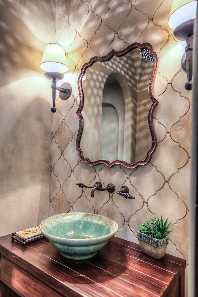 This is an example of a small mediterranean cloakroom in Houston with flat-panel cabinets, dark wood cabinets, a two-piece toilet, beige walls, terracotta flooring, a vessel sink, wooden worktops, red floors and brown worktops.