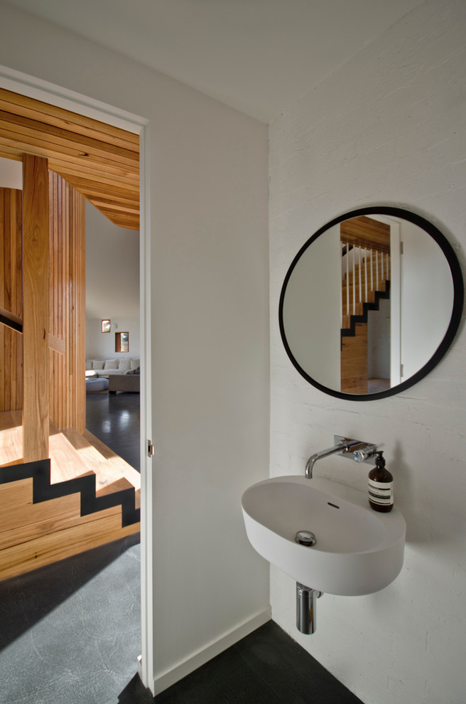 Idée de décoration pour un WC et toilettes design avec un lavabo suspendu et sol en béton ciré.