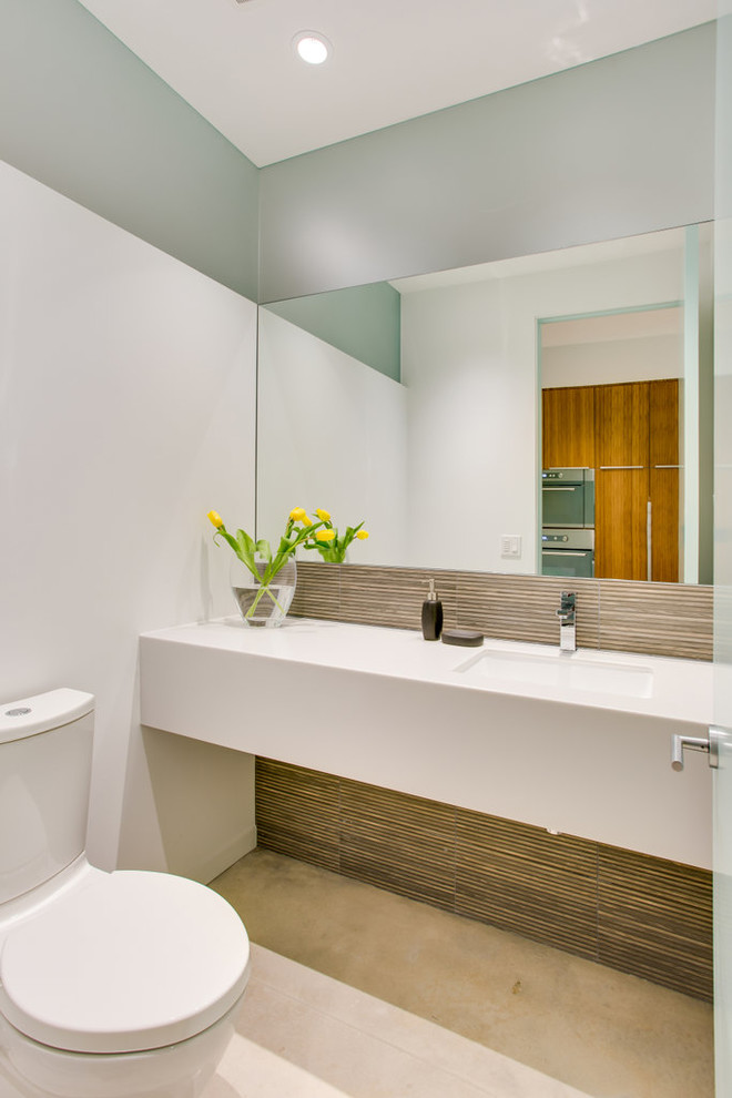 Inspiration for a medium sized modern cloakroom in Tampa with solid surface worktops, a two-piece toilet, concrete flooring, multi-coloured tiles, glass tiles, white walls and a submerged sink.