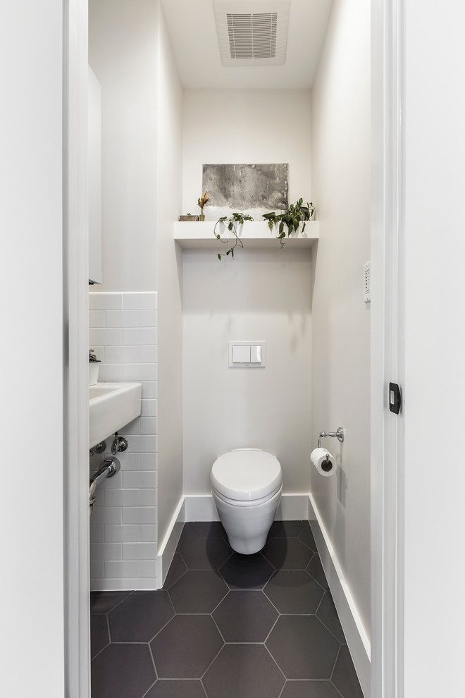 Idéer för att renovera ett litet funkis toalett, med ett väggmonterat handfat, vita skåp, en vägghängd toalettstol, vit kakel, svart kakel, vita väggar, klinkergolv i keramik och tunnelbanekakel