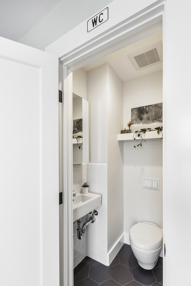 Idee per un piccolo bagno di servizio design con lavabo sospeso, ante bianche, WC sospeso, piastrelle bianche, piastrelle nere, piastrelle in ceramica e pareti bianche