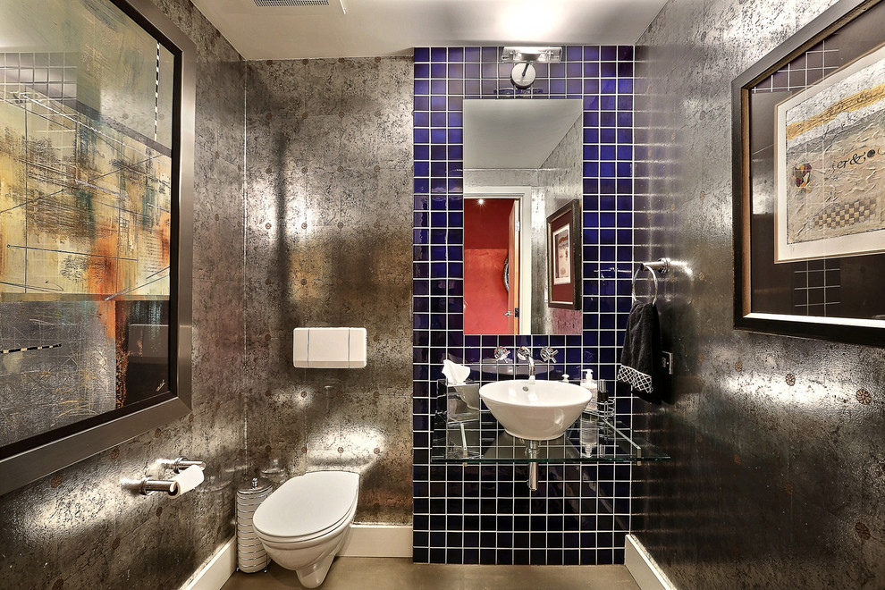 デンバーにあるインダストリアルスタイルのおしゃれなトイレ・洗面所 (ベッセル式洗面器、ガラスの洗面台、壁掛け式トイレ、青いタイル) の写真