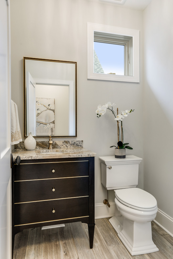 Bild på ett vintage beige beige toalett, med möbel-liknande, skåp i mörkt trä, en toalettstol med separat cisternkåpa, grå väggar, ljust trägolv, ett undermonterad handfat och grått golv