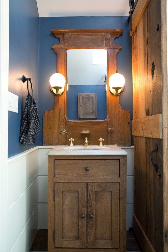 Exemple d'un petit WC et toilettes nature en bois brun avec un placard à porte shaker, un carrelage blanc, des carreaux de céramique, un mur bleu, un lavabo encastré, un plan de toilette blanc, meuble-lavabo sur pied et boiseries.