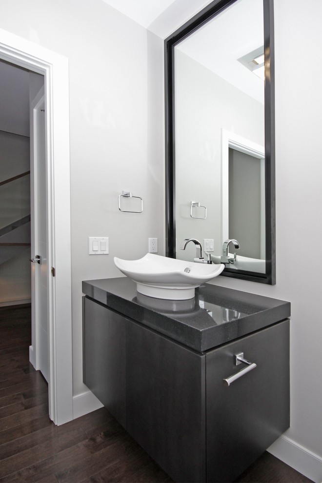 Ejemplo de aseo contemporáneo de tamaño medio con lavabo sobreencimera, sanitario de dos piezas, paredes grises, suelo de madera oscura, armarios con paneles lisos y puertas de armario grises