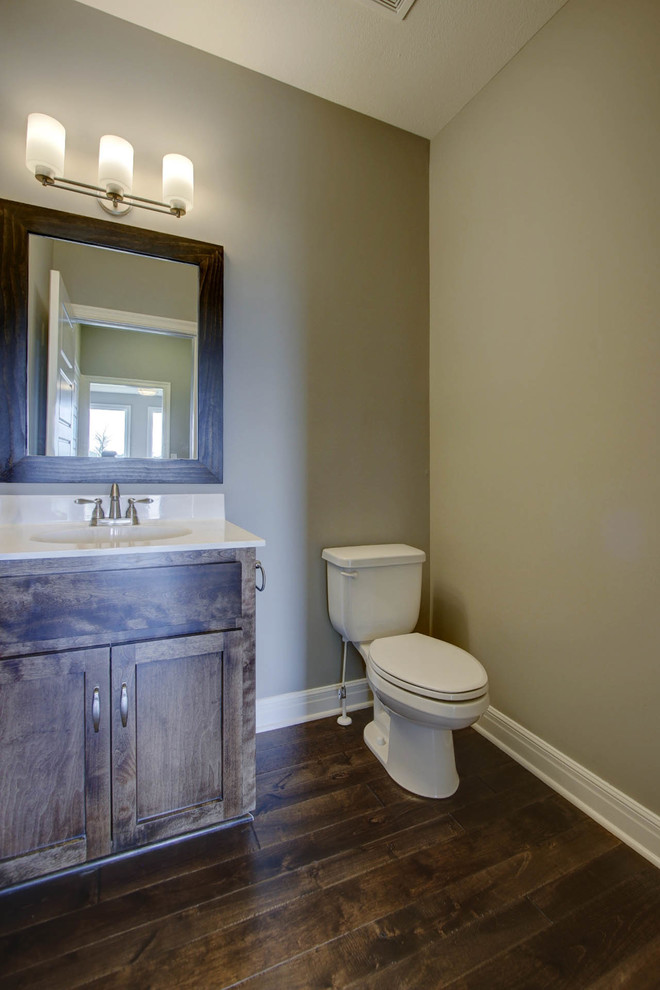 Idée de décoration pour un WC et toilettes craftsman en bois brun avec un placard à porte shaker, WC séparés, un mur gris, parquet foncé, un lavabo intégré, un plan de toilette en surface solide et un sol marron.