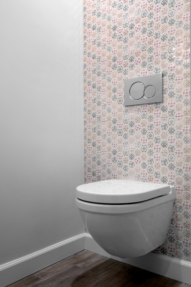 Inredning av ett litet vit vitt toalett, med släta luckor, skåp i mörkt trä, en vägghängd toalettstol, flerfärgad kakel, porslinskakel, grå väggar, ljust trägolv, ett integrerad handfat, bänkskiva i akrylsten och beiget golv