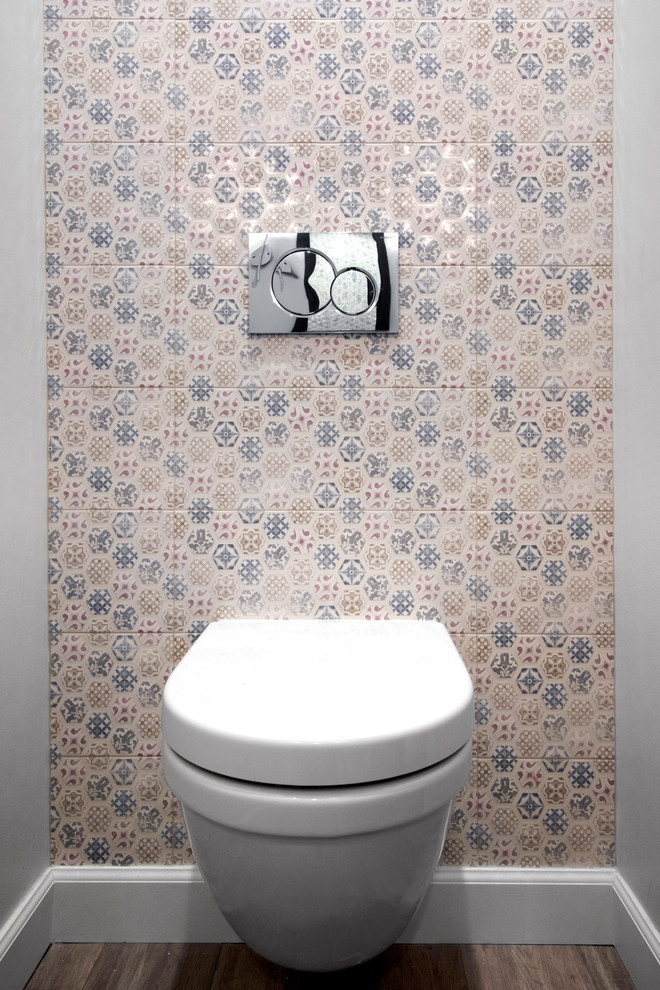 Cette photo montre un petit WC suspendu en bois foncé avec un placard à porte plane, un carrelage multicolore, des carreaux de porcelaine, un mur gris, parquet clair, un lavabo intégré, un plan de toilette en surface solide, un sol beige et un plan de toilette blanc.