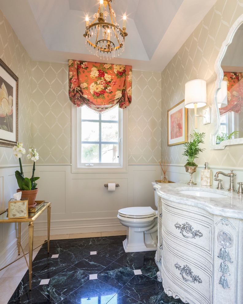 Ispirazione per un bagno di servizio tradizionale con lavabo sottopiano, consolle stile comò, piastrelle beige, piastrelle nere, pareti beige, ante con finitura invecchiata e top bianco