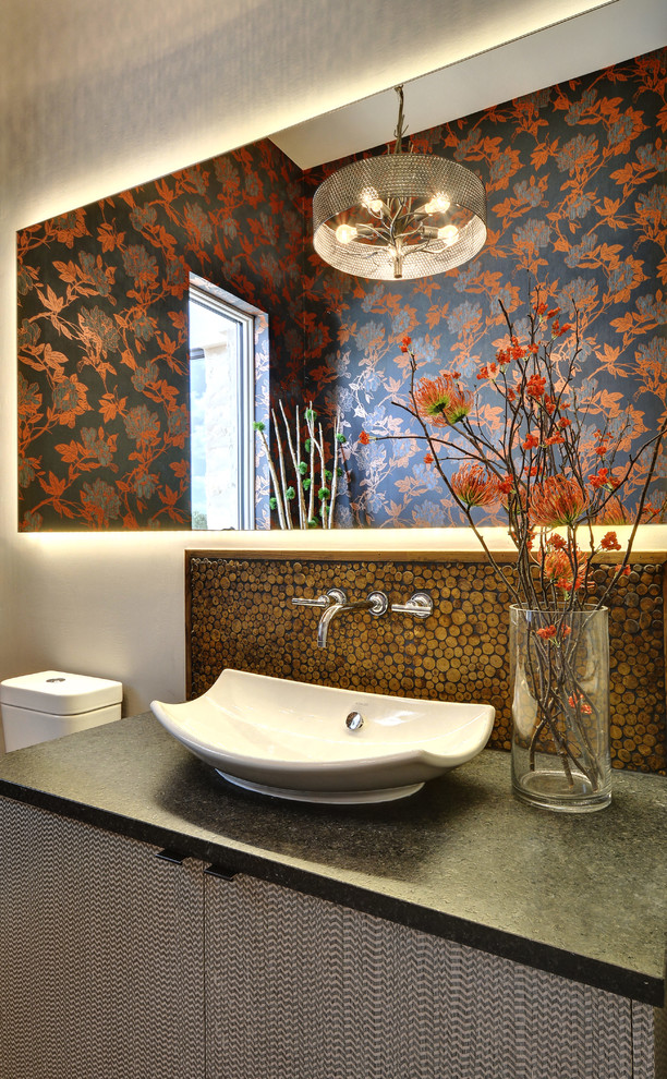 Immagine di un bagno di servizio minimal di medie dimensioni con lavabo a bacinella, ante lisce, ante grigie, top in granito, piastrelle marroni, piastrelle a mosaico e pareti grigie