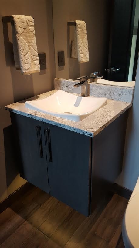 Design ideas for a small modern cloakroom in Cedar Rapids with flat-panel cabinets, solid surface worktops, a one-piece toilet, grey walls, dark hardwood flooring, a built-in sink, black cabinets and grey worktops.
