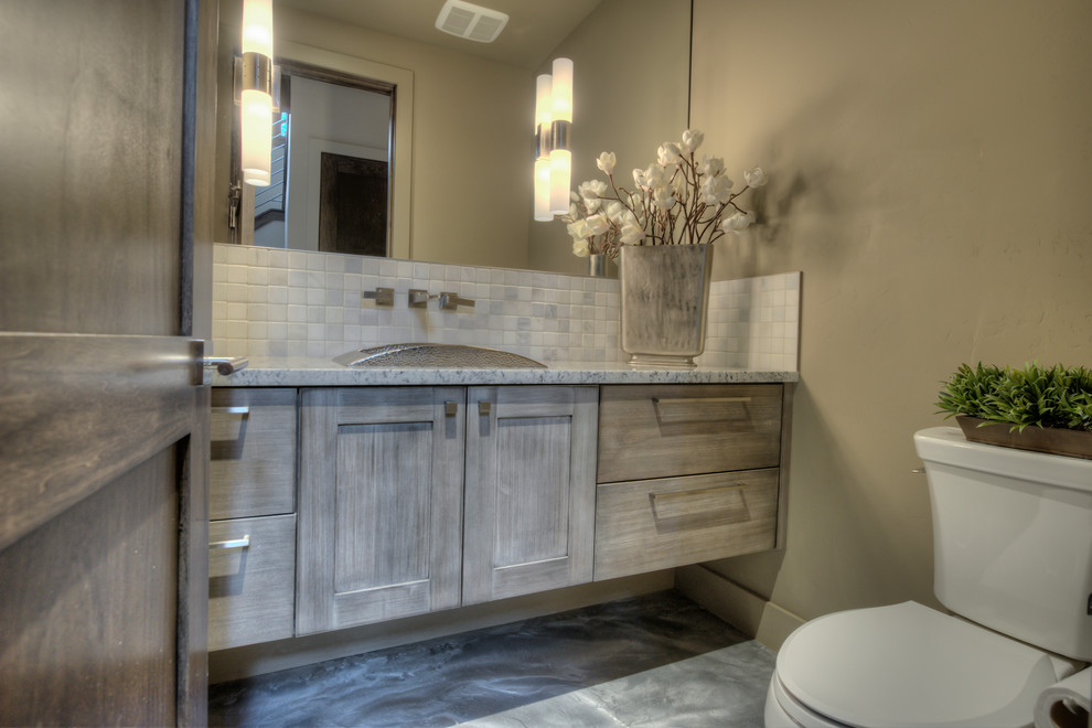 Inspiration for a transitional gray tile concrete floor powder room remodel in Denver with recessed-panel cabinets, a two-piece toilet, beige walls, a drop-in sink, granite countertops and light wood cabinets