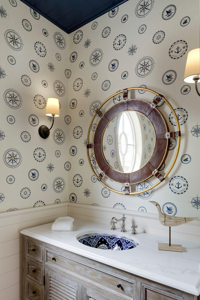 Idee per un bagno di servizio stile marinaro con consolle stile comò, ante in legno chiaro, pareti multicolore e lavabo sottopiano