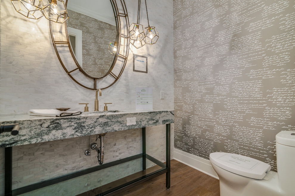 Foto på ett mellanstort vintage flerfärgad toalett, med en toalettstol med hel cisternkåpa, vit kakel, mosaik, grå väggar, mörkt trägolv, ett undermonterad handfat, granitbänkskiva och brunt golv