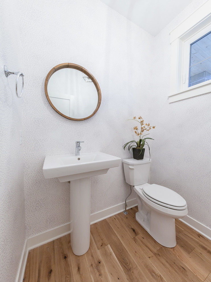 Idee per un piccolo bagno di servizio tradizionale con WC a due pezzi, pareti bianche, pavimento in legno massello medio, lavabo a colonna, top in superficie solida e pavimento marrone