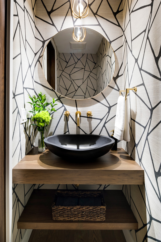 Photo of a small modern cloakroom in Minneapolis with open cabinets, medium wood cabinets, a one-piece toilet, light hardwood flooring, a vessel sink, wooden worktops, grey floors and brown worktops.