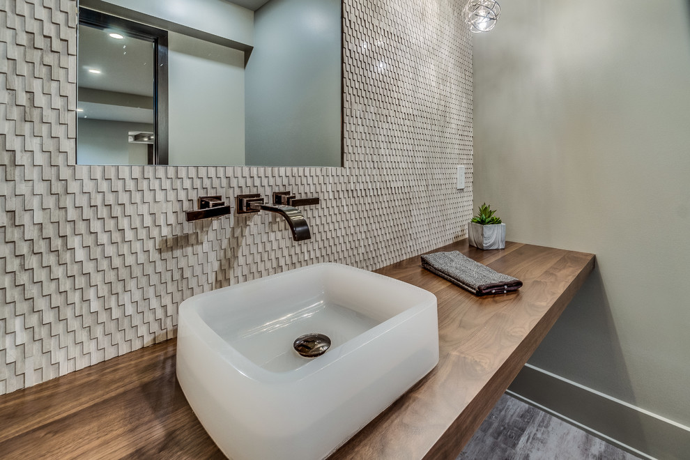 На фото: туалет среднего размера в стиле модернизм с серой плиткой, плиткой мозаикой, серыми стенами, полом из керамогранита, настольной раковиной, столешницей из дерева, серым полом и коричневой столешницей с