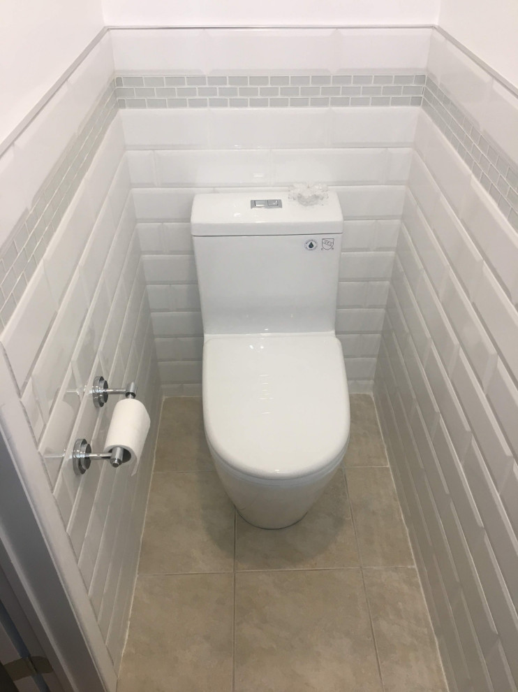 Idéer för att renovera ett litet grön grönt toalett, med luckor med infälld panel, vita skåp, en toalettstol med hel cisternkåpa, vit kakel, tunnelbanekakel, vita väggar, klinkergolv i porslin, ett integrerad handfat, bänkskiva i glas och beiget golv