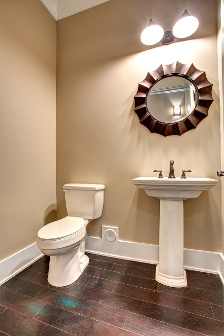 На фото: туалет среднего размера в стиле неоклассика (современная классика) с раздельным унитазом, бежевыми стенами, темным паркетным полом, раковиной с пьедесталом и коричневым полом