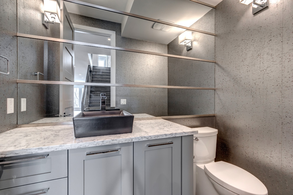 Cette image montre un WC et toilettes design de taille moyenne avec un placard à porte shaker, des portes de placard grises, WC séparés, un mur gris, un sol en bois brun, une vasque, un plan de toilette en quartz modifié et un sol marron.