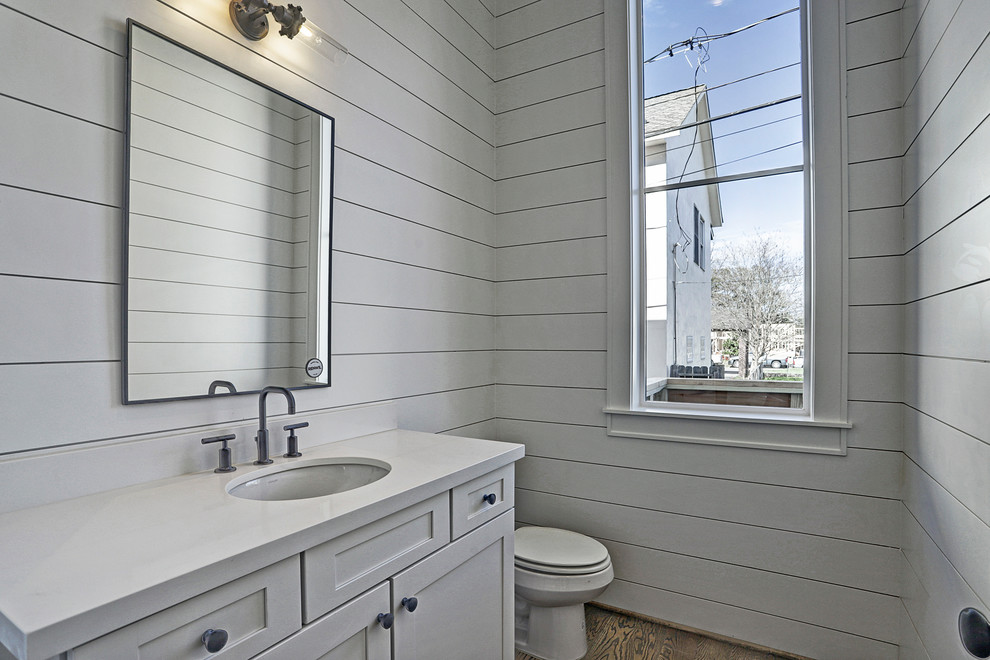 Photo of a small rural cloakroom in Houston with shaker cabinets, white cabinets, a two-piece toilet, white walls, dark hardwood flooring, a submerged sink, solid surface worktops, brown floors and white worktops.