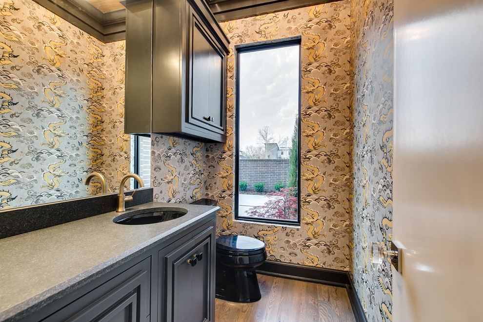 This is an example of an expansive modern cloakroom in Oklahoma City with shaker cabinets, black cabinets, a one-piece toilet, medium hardwood flooring, granite worktops and black worktops.