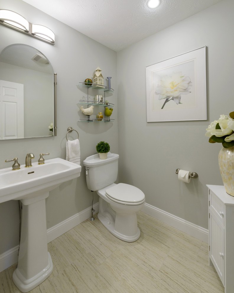 Inredning av ett klassiskt toalett, med en toalettstol med separat cisternkåpa, grå väggar, klinkergolv i porslin, ett piedestal handfat och grått golv