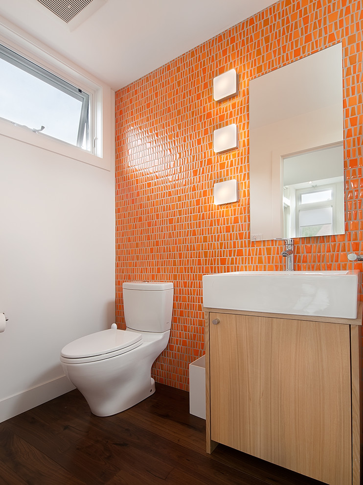 Пример оригинального дизайна: туалет среднего размера в современном стиле с монолитной раковиной, плоскими фасадами, светлыми деревянными фасадами, раздельным унитазом, оранжевой плиткой, керамической плиткой, белыми стенами и темным паркетным полом