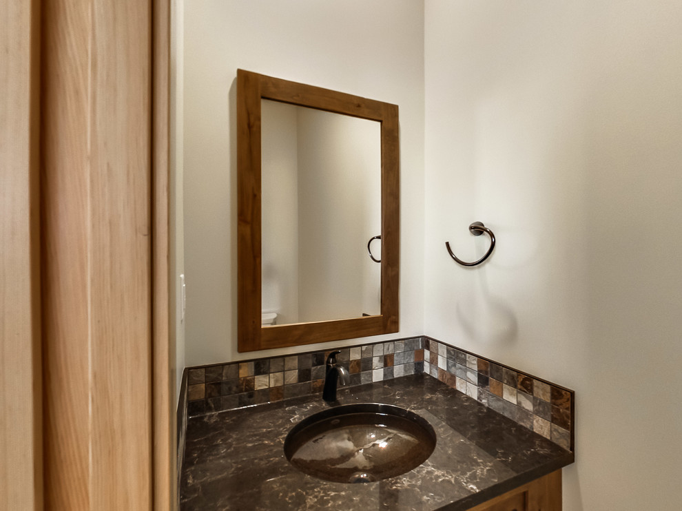Cette photo montre un petit WC et toilettes craftsman en bois brun avec un placard à porte shaker, un carrelage multicolore, un lavabo encastré et un plan de toilette en quartz.