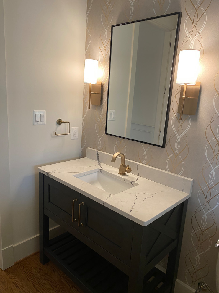 Powder room - mid-sized transitional medium tone wood floor, brown floor and wallpaper powder room idea in DC Metro with shaker cabinets, gray cabinets, a two-piece toilet, white walls, an undermount sink, quartz countertops, white countertops and a freestanding vanity