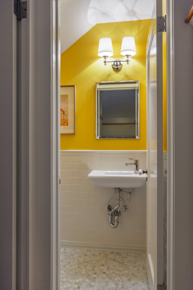 Klassisk inredning av ett litet toalett, med vit kakel, keramikplattor, gula väggar, ett väggmonterat handfat och marmorgolv