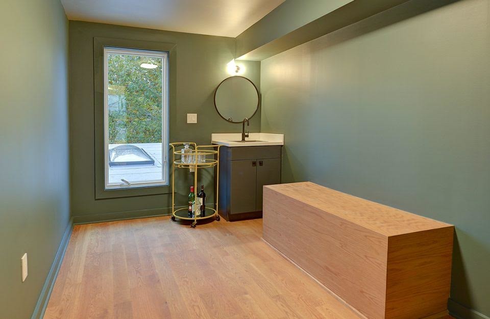 Medium sized traditional cloakroom in DC Metro with flat-panel cabinets, green cabinets, green walls, medium hardwood flooring, a submerged sink, solid surface worktops, brown floors and white worktops.