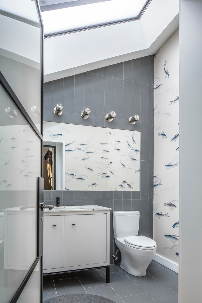 Idee per un bagno di servizio contemporaneo con ante lisce, ante bianche, WC a due pezzi, piastrelle grigie e pavimento grigio