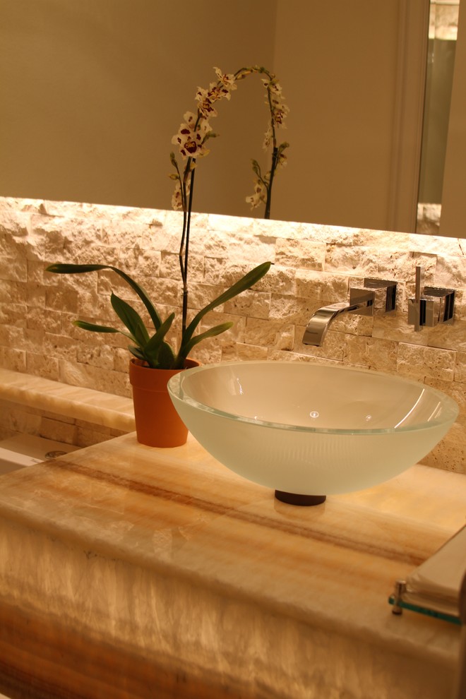Exempel på ett litet modernt toalett, med ett fristående handfat, bänkskiva i onyx, en toalettstol med separat cisternkåpa, beige kakel och stenkakel