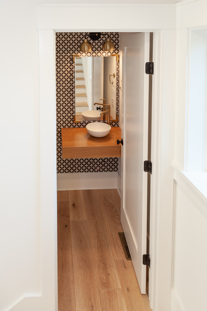 Diseño de aseo minimalista de tamaño medio con suelo de madera clara, lavabo sobreencimera, encimera de madera, paredes multicolor, suelo marrón y encimeras marrones