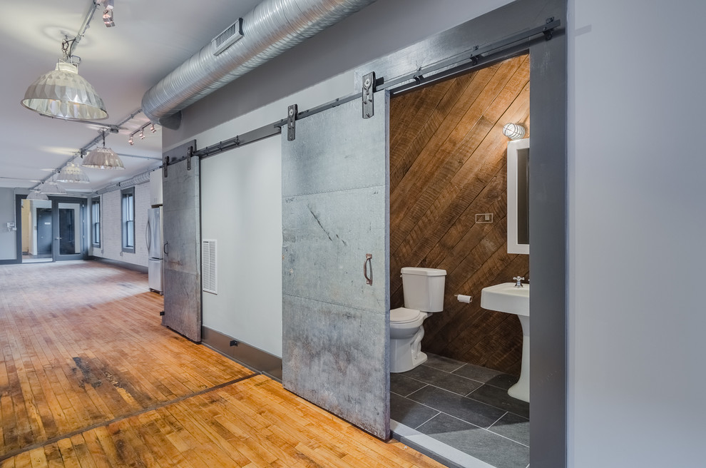 Immagine di un bagno di servizio industriale di medie dimensioni con WC a due pezzi, piastrelle grigie, pareti grigie, pavimento in ardesia e lavabo a colonna