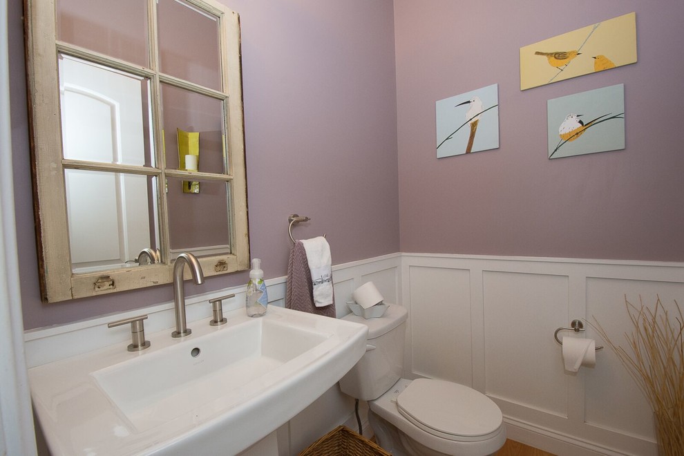 Bild på ett litet vintage toalett, med en toalettstol med hel cisternkåpa, mellanmörkt trägolv, ett piedestal handfat, brunt golv och rosa väggar