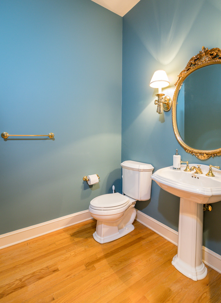 Mittelgroße Klassische Gästetoilette mit Wandtoilette mit Spülkasten, blauer Wandfarbe, hellem Holzboden und Sockelwaschbecken in Charleston