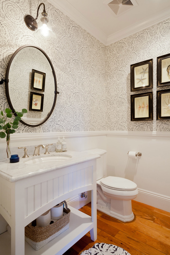 Inspiration pour un petit WC et toilettes traditionnel avec un placard à porte affleurante, des portes de placard blanches, WC séparés, un sol en bois brun, un lavabo encastré et un plan de toilette en marbre.