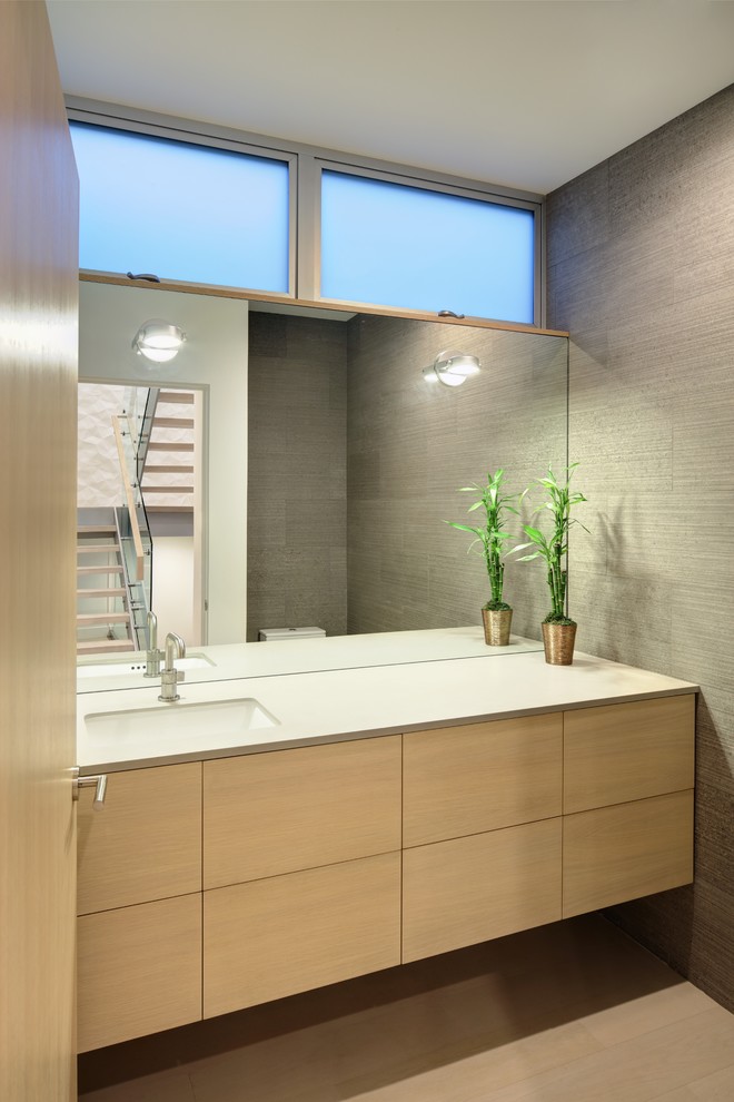 This is an example of a small scandi cloakroom in Los Angeles with flat-panel cabinets, light wood cabinets, light hardwood flooring, granite worktops, beige floors, white worktops, grey walls and a submerged sink.