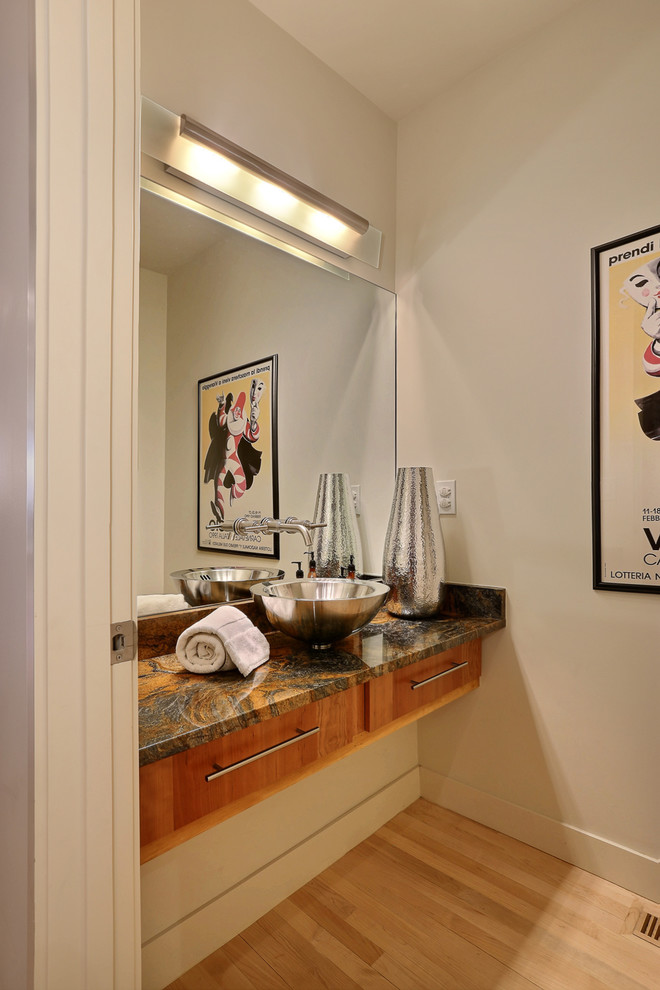 Ejemplo de aseo contemporáneo con lavabo sobreencimera, armarios con paneles lisos, puertas de armario de madera oscura, paredes beige y suelo de madera clara