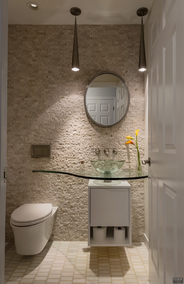 Idées déco pour un petit WC et toilettes moderne avec un placard à porte plane, des portes de placard blanches, WC à poser, un carrelage beige, un carrelage de pierre, un mur beige, un sol en carrelage de terre cuite, une vasque, un plan de toilette en verre et un sol beige.