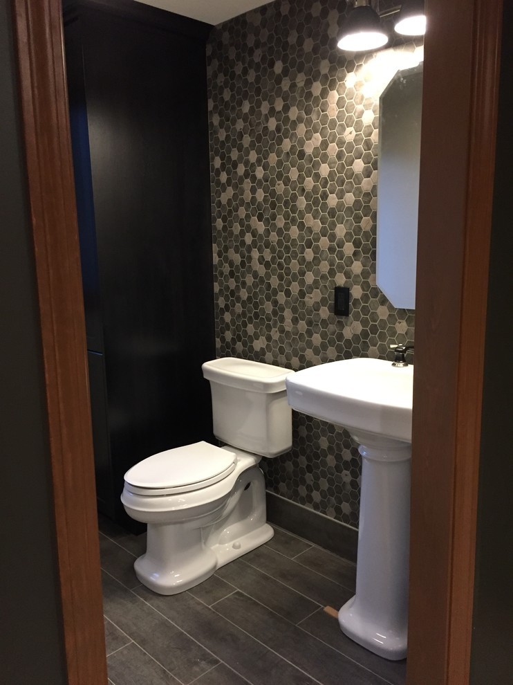 На фото: туалет в стиле неоклассика (современная классика) с черными фасадами, раздельным унитазом, серой плиткой, керамогранитной плиткой, серыми стенами, полом из керамогранита и раковиной с пьедесталом с